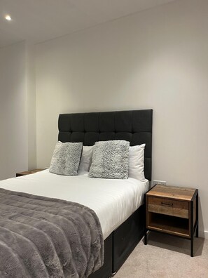Une chambre moderne avec un grand lit, deux tables de chevet et une tête de lit.