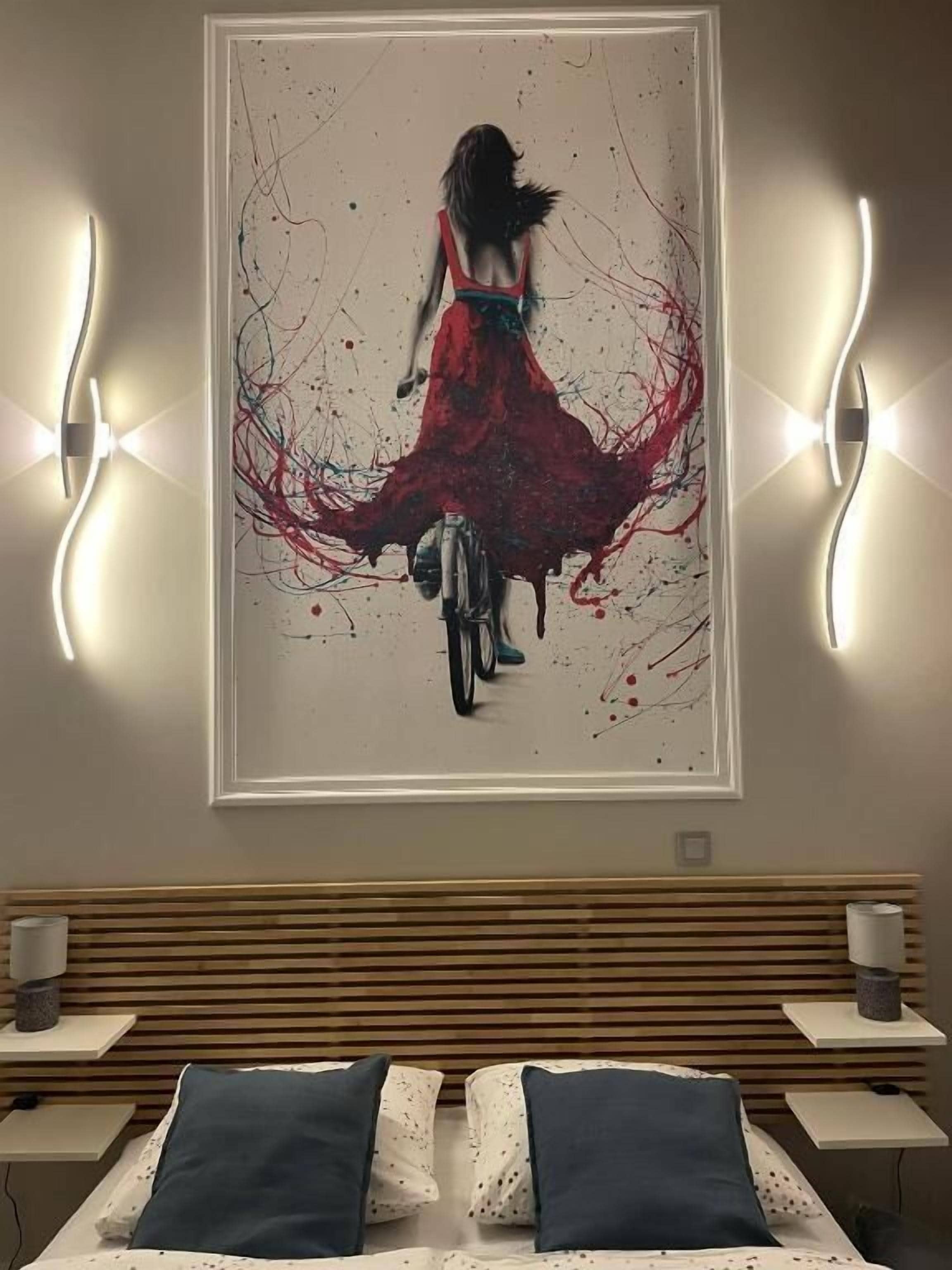 A bedroom with a bed, bedside tables, a headboard, and a large abstract painting on the wall.