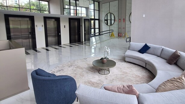 Un interior modern amb un sofà gris corbat, una cadira blava i una taula de centre.