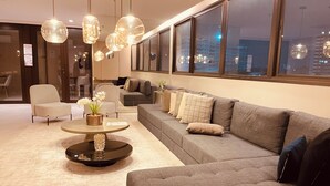 Un saló modern amb un sofà gris, una taula de centre rodona i llums esfèriques penjants.