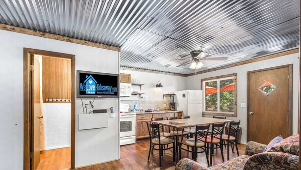 A compact kitchen with a dining area, a television, and a ceiling fan. - Skyline Cabin - Lakefront Table Rock Lake (Galena)