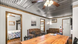 A room with a wooden dining table, two patterned sofas, a ceiling fan, and a television. - Skyline Cabin - Lakefront Table Rock Lake (Galena)