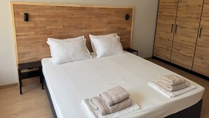 Un letto rifatto con cuscini, un comodino e un armadio in una camera d'albergo.