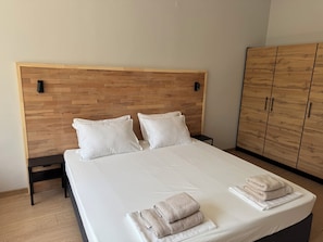 Una cama bien hecha con almohadas, una mesita de noche y un armario en una habitación de hotel.
