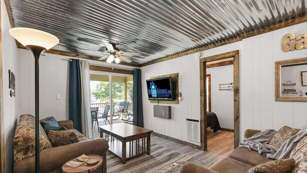 Un soggiorno con divano, tavolino, lampada, televisore e ventilatore a soffitto.