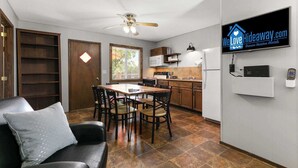 Eine kompakte Küche mit Essbereich, Deckenventilator und an der Wand montiertem Fernseher.