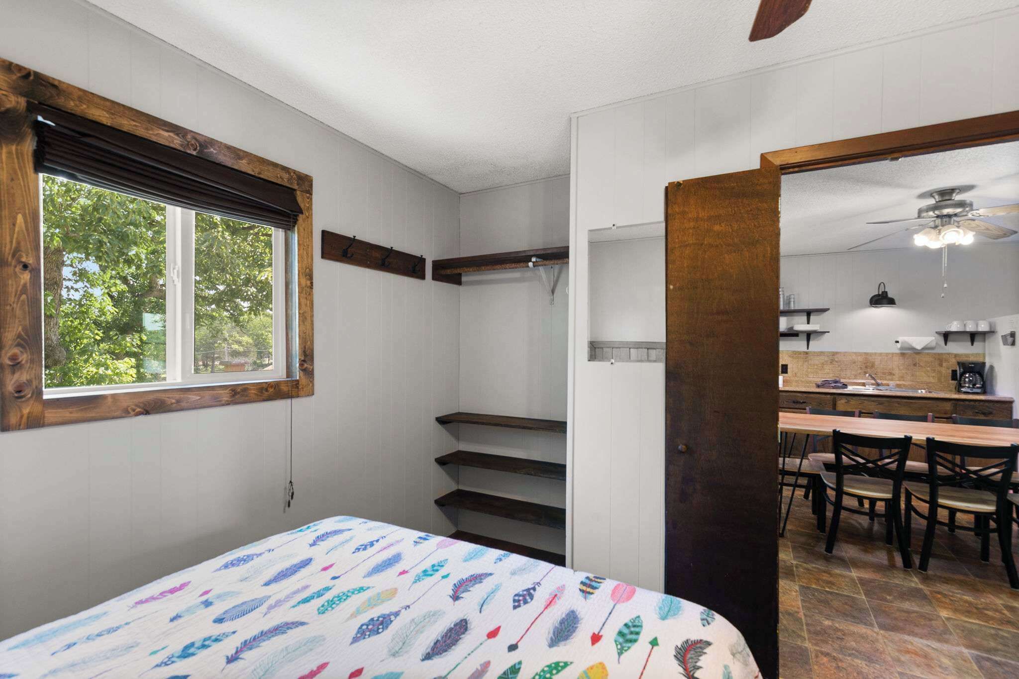 Ein Schlafzimmer mit Bett, Fenster, Treppe und Blick auf eine Küche.