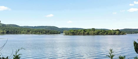 A calm lake with a small island in the center, surrounded by forested hills.