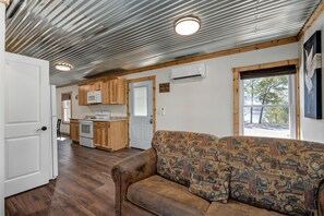 A compact kitchen with wooden cabinets, a microwave, and a stove. - Blue Heron · Lakefront Cabin · Pool & Dock (Galena)
