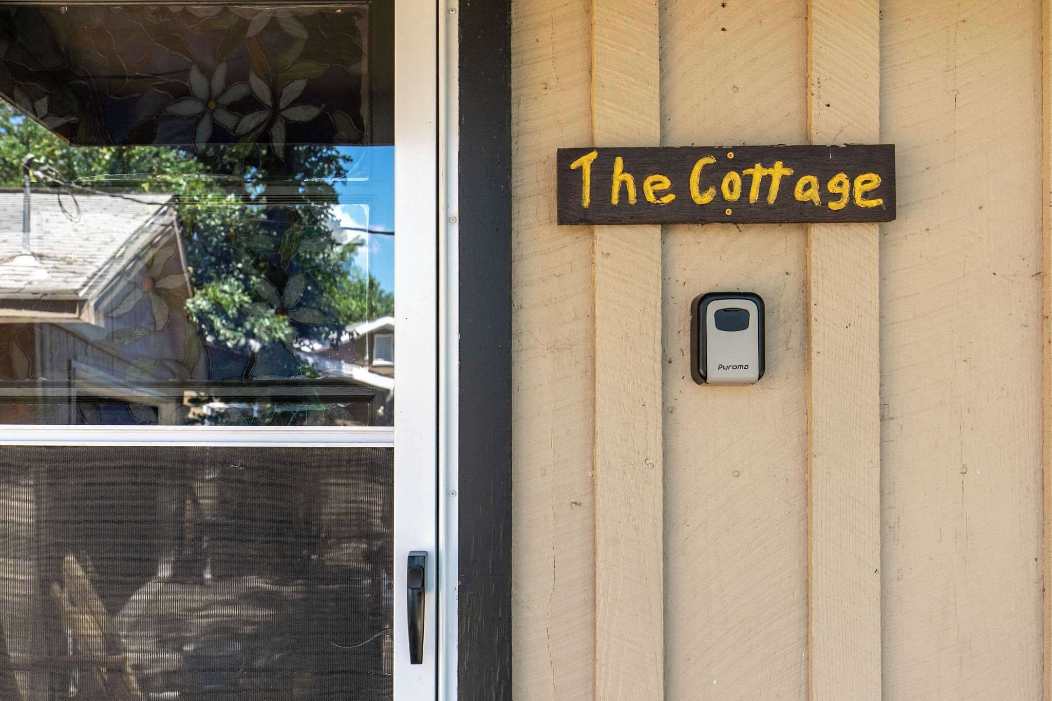 Pared de madera con un letrero que dice 'The Cottage' y un timbre.