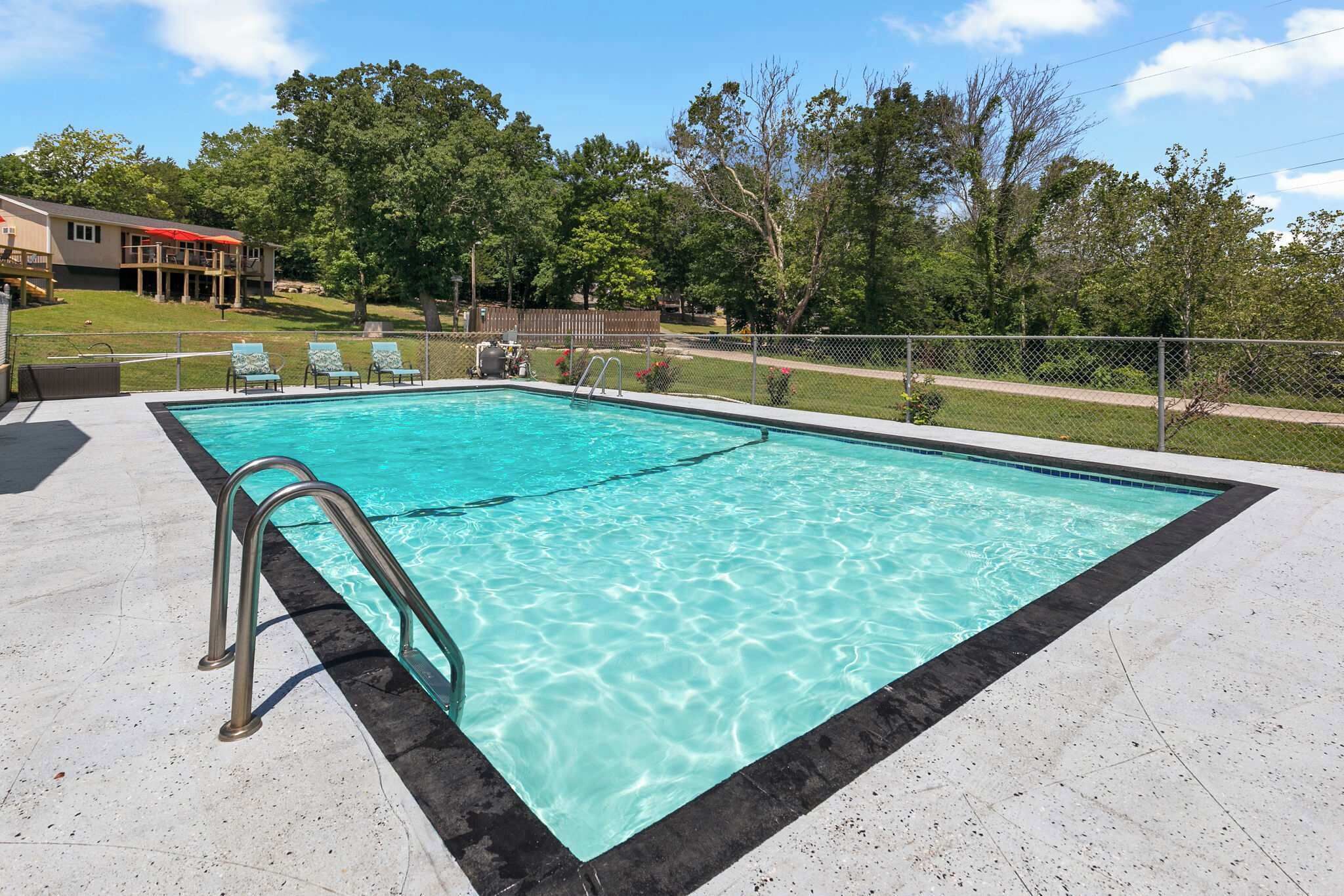 Ein rechteckiger Pool mit schwarzem Rand, umgeben von einer gepflasterten Terrasse.