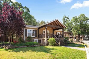 A two-story house with a covered porch, a staircase, and a well-maintained lawn. - Lakefront 4BR · Pool · Resort Dock · Sleeps 12 (Galena)