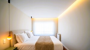 Una camera d'albergo con un letto, una lampada da comodino e una finestra con tende.