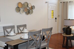 Un coin repas avec une table en bois, des chaises grises et un élément décoratif mural.