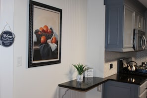 Une cuisine avec un tableau encadré, un panneau d’accueil, une plante en pot et une cuisinière.