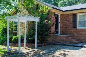 A house with a brick exterior, a white pergola, and pink flowers. - Mint Hill Luxury Retreat / Near Charlotte/4BR/3BA (Mint Hill)