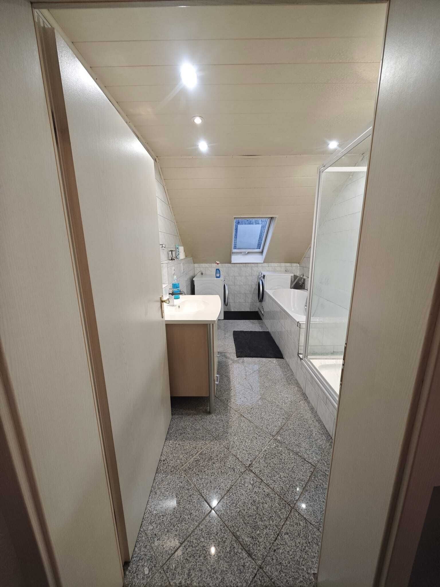 A narrow bathroom with a sink, mirror, and window.