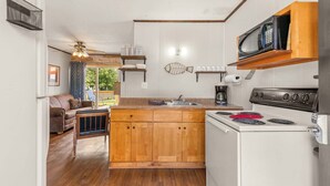 Una cucina con mobili in legno, un fornello, un forno a microonde e una decorazione a forma di pesce sul muro.