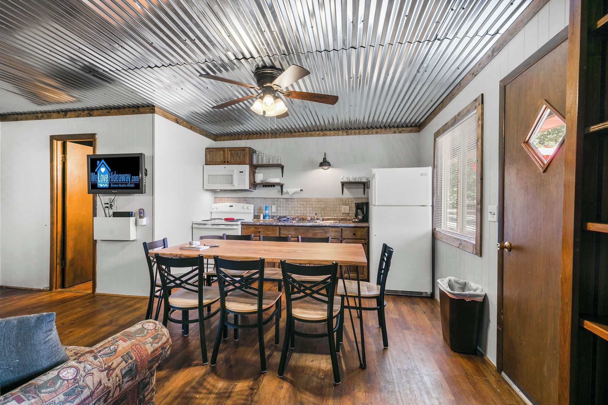 Una cocina compacta con una mesa de comedor, sillas y un ventilador de techo.