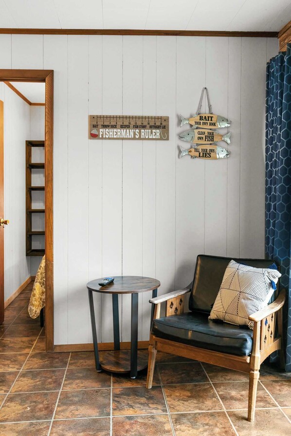 A room with a wooden chair, a small table, and a wall with fish-themed decorations.