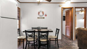 Un espace repas comprenant une table et des chaises, un réfrigérateur et un panneau fixé au mur indiquant les sentiers de randonnée.