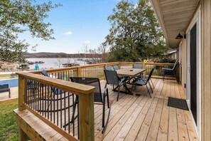 A wooden deck with outdoor furniture, a view of a lake, and docked boats.