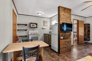 A compact kitchen with a wooden table, a microwave, a stove, and a refrigerator.