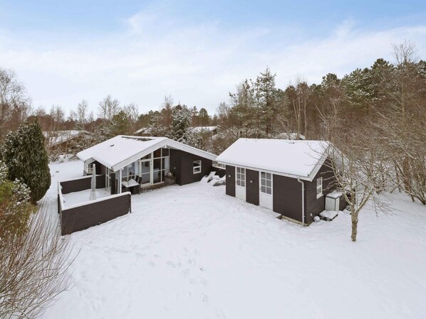 Ein zweistöckiges Haus mit verschneitem Dach und Garage.