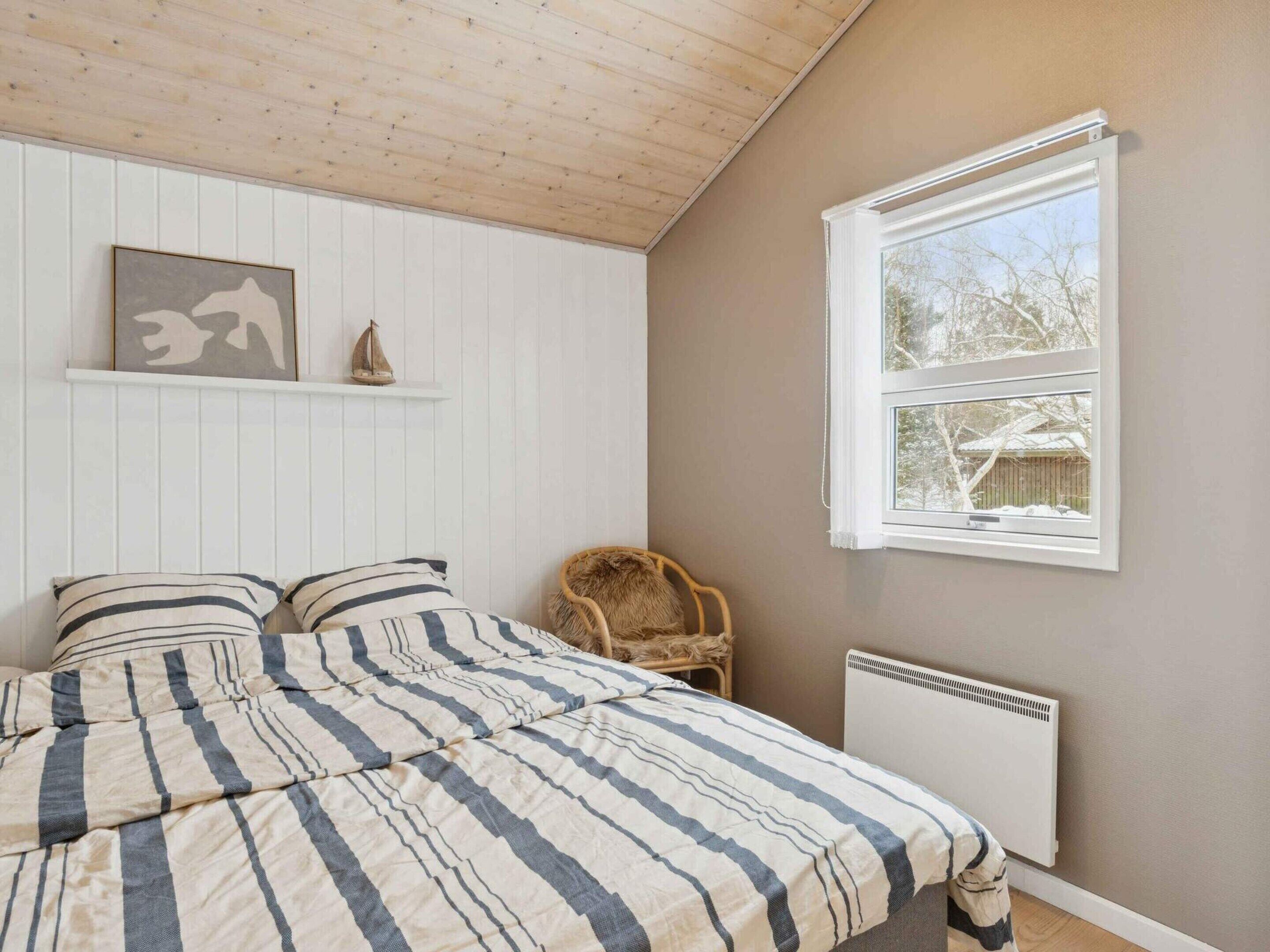 A bedroom with a bed, a chair, a window, and a radiator.