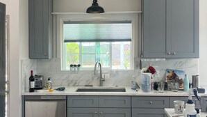 A kitchen with grey cabinets, a window with blinds, a stainless steel sink, a dishwasher, and a stove. - Wonderful 2-bedroom house with Zonal Mini Splits , tree lined nieghborhood (Phoenix)