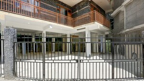 A gated courtyard with a brick floor, a stone pillar, and a multi-level building with balconies.