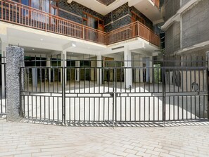 Une courClose, dotée d’un sol en briques, d’un pilier en pierre et d’un immeuble à plusieurs niveaux avec des balcons.