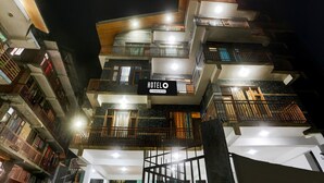 A multi-story hotel with balconies, a sign indicating it's a company-serviced hotel, and a well-lit facade.