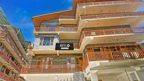 A multi-story hotel with balconies, a sign indicating it's a company-serviced hotel, and a clear blue sky.