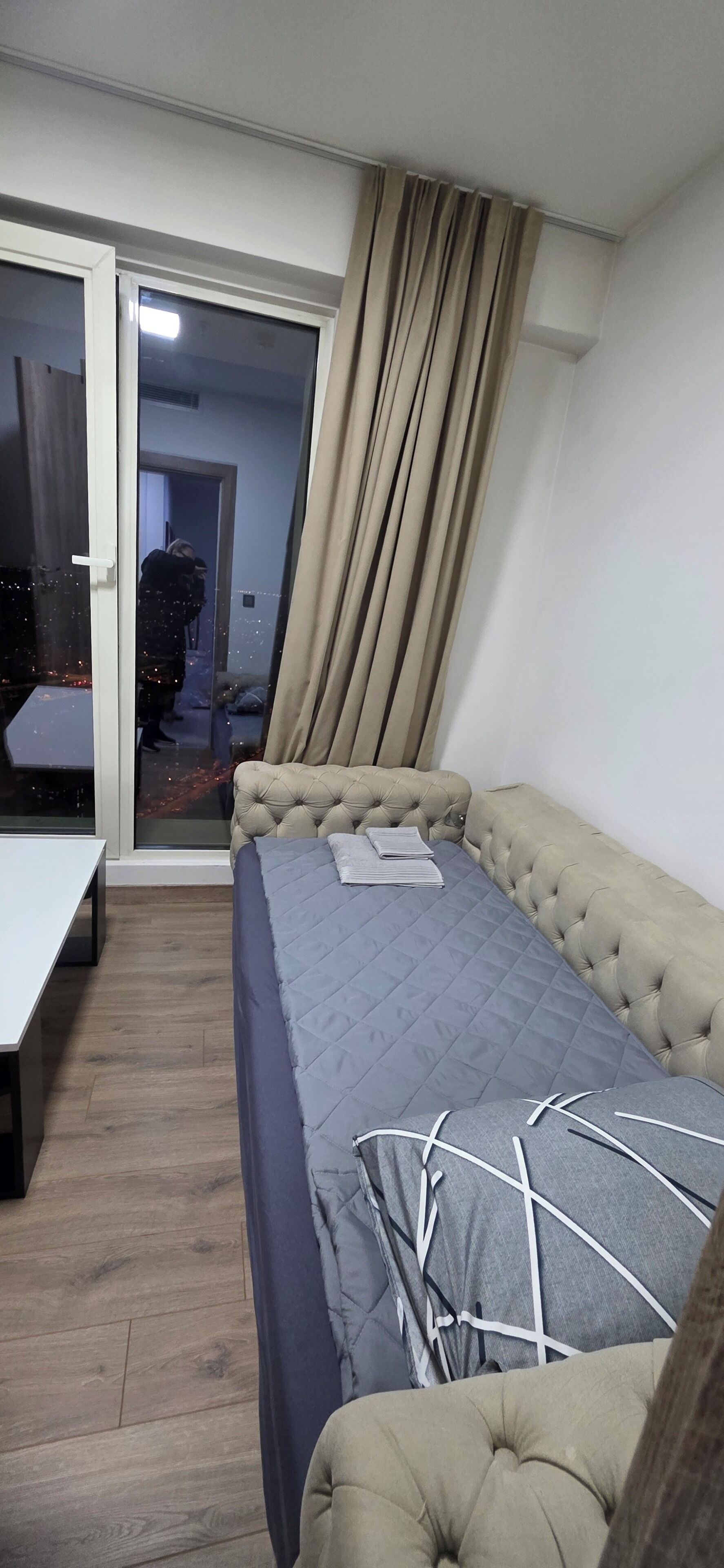 Een slaapkamer met een bed, een tafel en een schuifdeur die uitkomt op een gang.