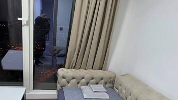 Een slaapkamer met een bed, een tafel en een schuifdeur die uitkomt op een gang.