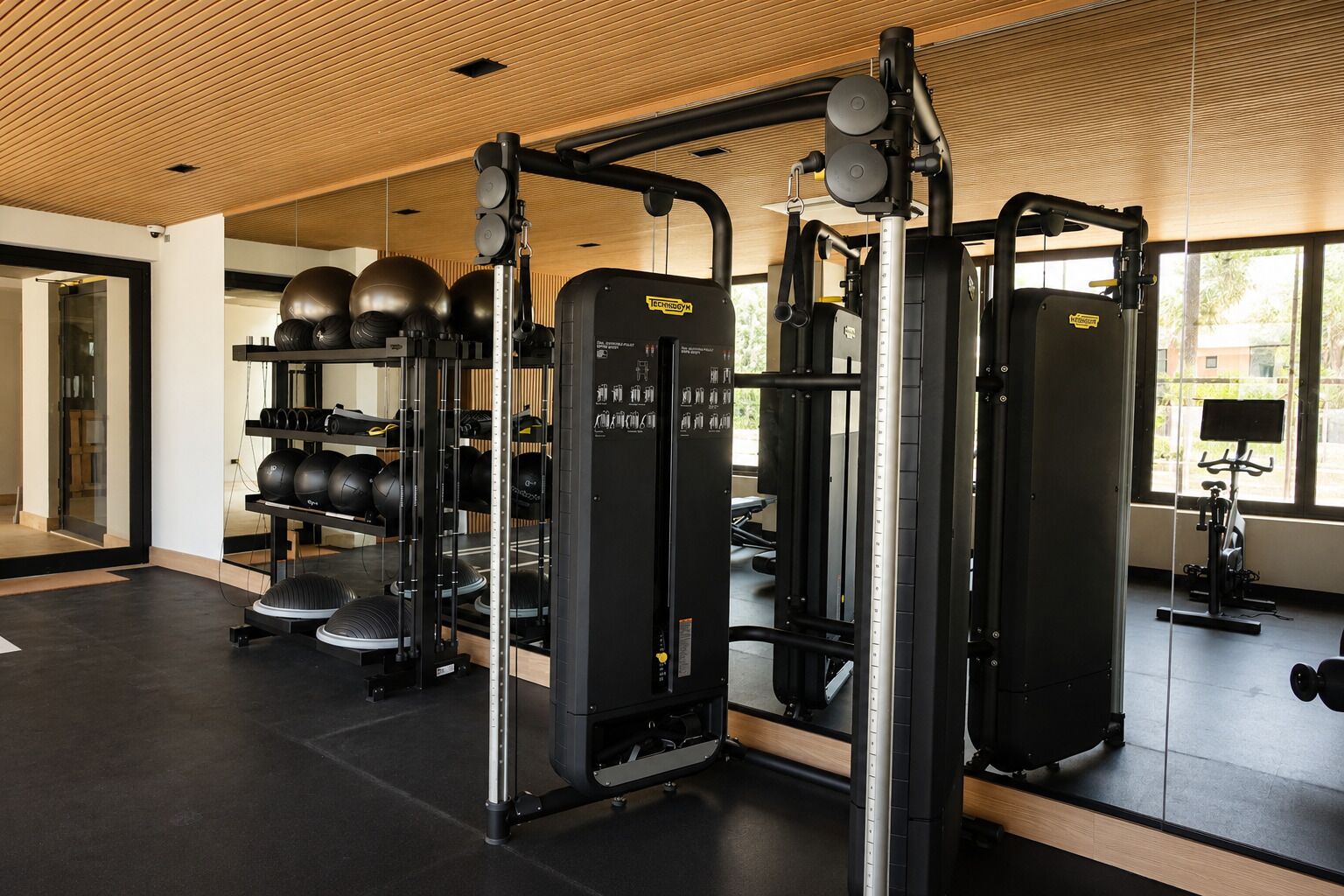 A gym with weightlifting equipment, exercise balls, and a stationary bike.