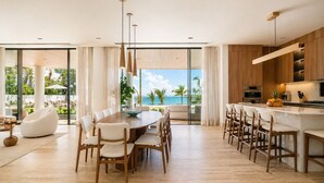 Une cuisine moderne dotée d’un grand îlot central, de meubles en bois et offrant une vue sur l’océan.