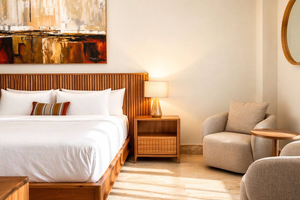 A hotel room with a bed, a nightstand with a lamp, a chair, and a round table.