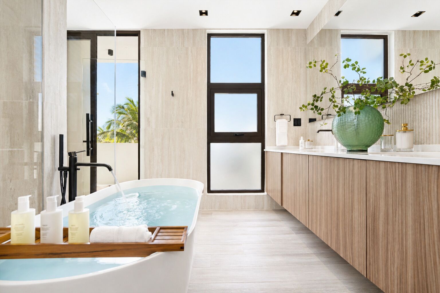 A modern bathroom with a freestanding bathtub, a wooden vanity, and a large window.