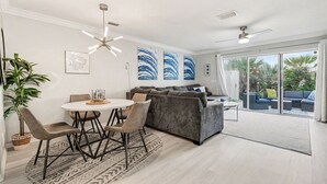 Ein modernes Wohnzimmer mit Essbereich, einem grauen Sofa und einer großen Glasschiebetür, die auf eine Außenpatio führt.