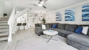 Ein modernes Wohnzimmer mit einem grauen Sofa, einem Couchtisch und einer Treppe mit weißen Geländern.