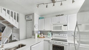 Eine moderne Küche mit weißen Schränken, einem eingebauten Backofen, einer Mikrowelle und einer Spüle aus Edelstahl.