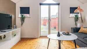 A modern living room with a TV, sofa, and a table with decorative items. - 8 Person Holiday Home in Hadsund (Hadsund)