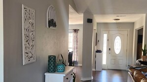 A spacious hallway with a white console table, decorative wall art, and a door leading to another room. - Rexford Sound HideAway-Pool and Pet Friendly (Navarre)