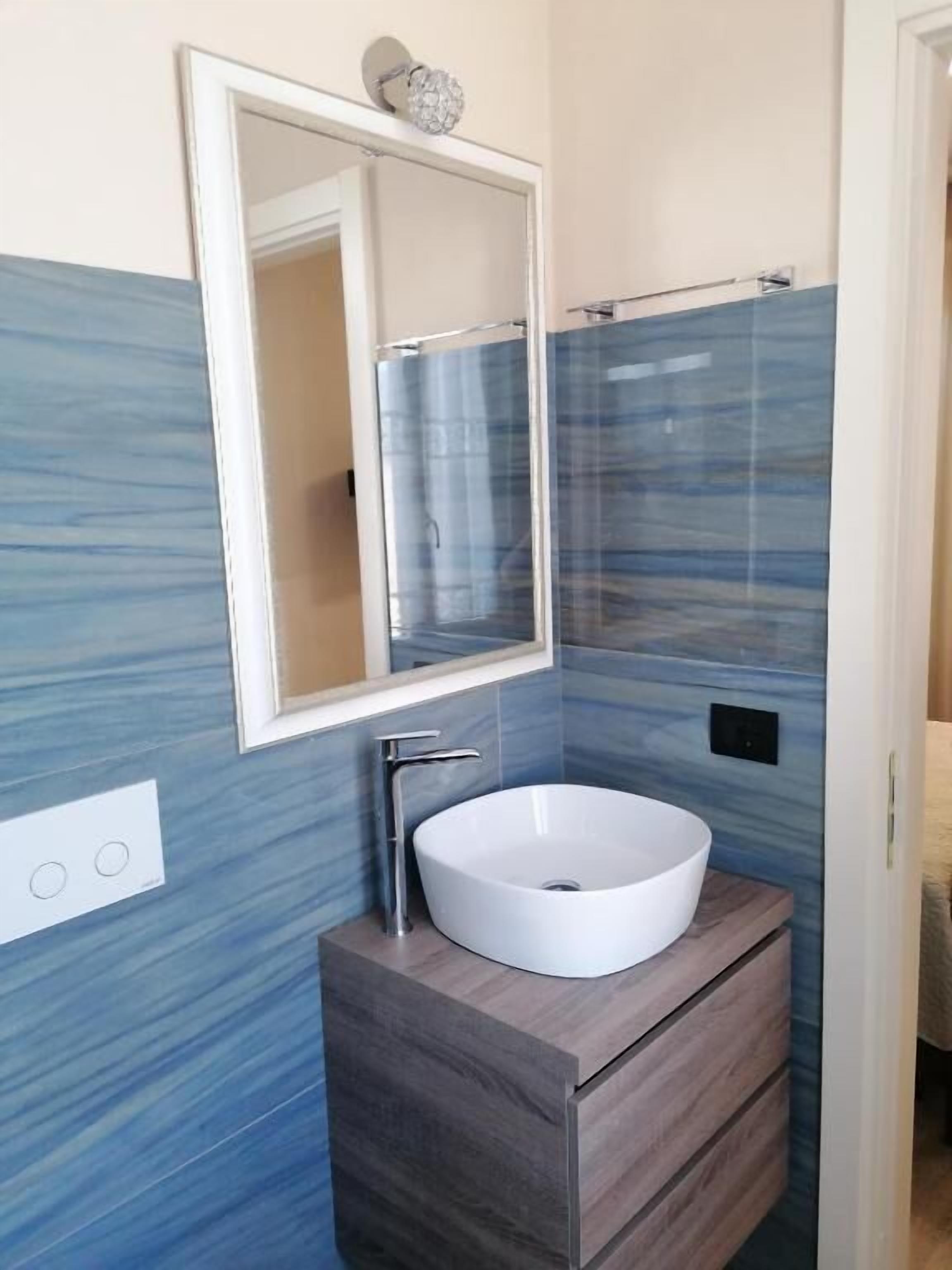 A bathroom with a white sink, a mirror, and blue patterned walls.