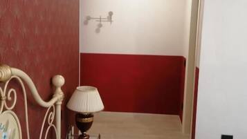 Une chambre d’hôtel avec un lit, une lampe, un climatiseur fixé au mur, et une décoration aux couleurs rouge et blanche.