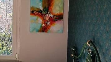 Una camera da letto con un letto, una finestra, un quadro e una parete scura con motivo.