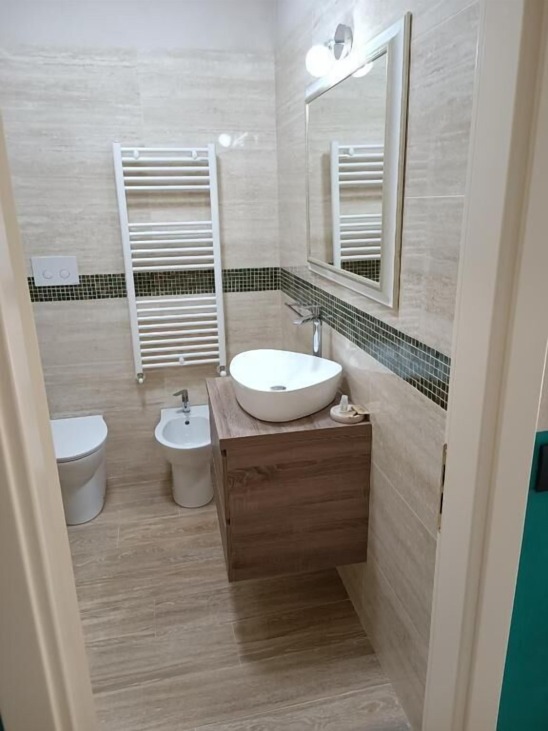 Ein Badezimmer mit Toilette, Bidet und Waschbecken mit Holzschrank.