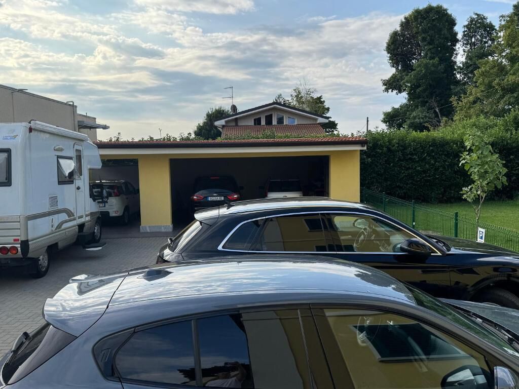 Un espace de stationnement avec un bâtiment jaune, un camping-car blanc et une voiture noire.